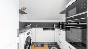 A modern kitchen with a washing machine, microwave, and oven. - Apartment '3' Villa Elysium (Heide)