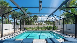 Une piscine couverte avec des chaises longues et vue sur les palmiers.