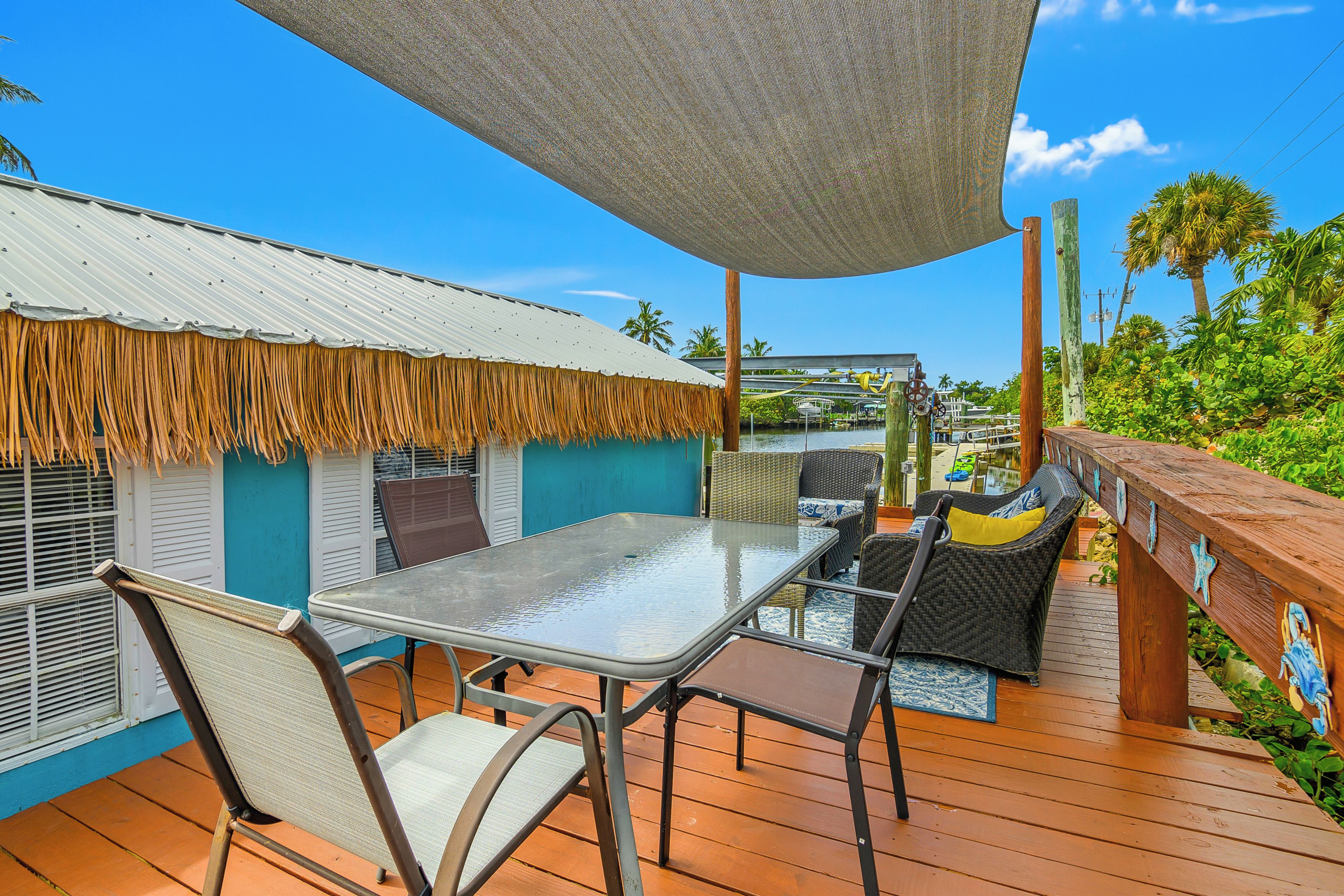 A deck with a table and chairs, a thatched roof, and a view of the water.