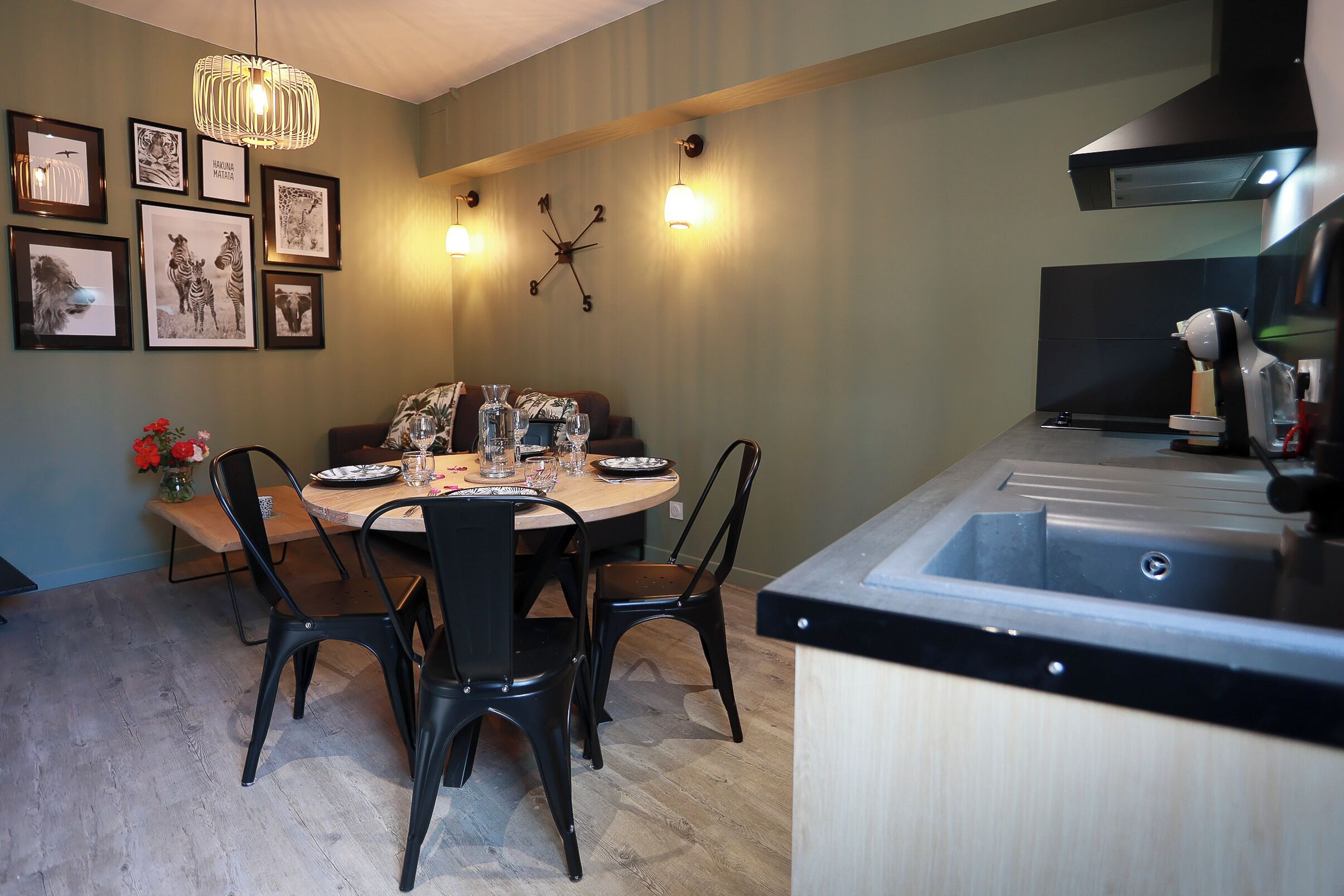 Un coin repas avec une table ronde, des chaises noires et des œuvres d’art encadrées accrochées au mur.