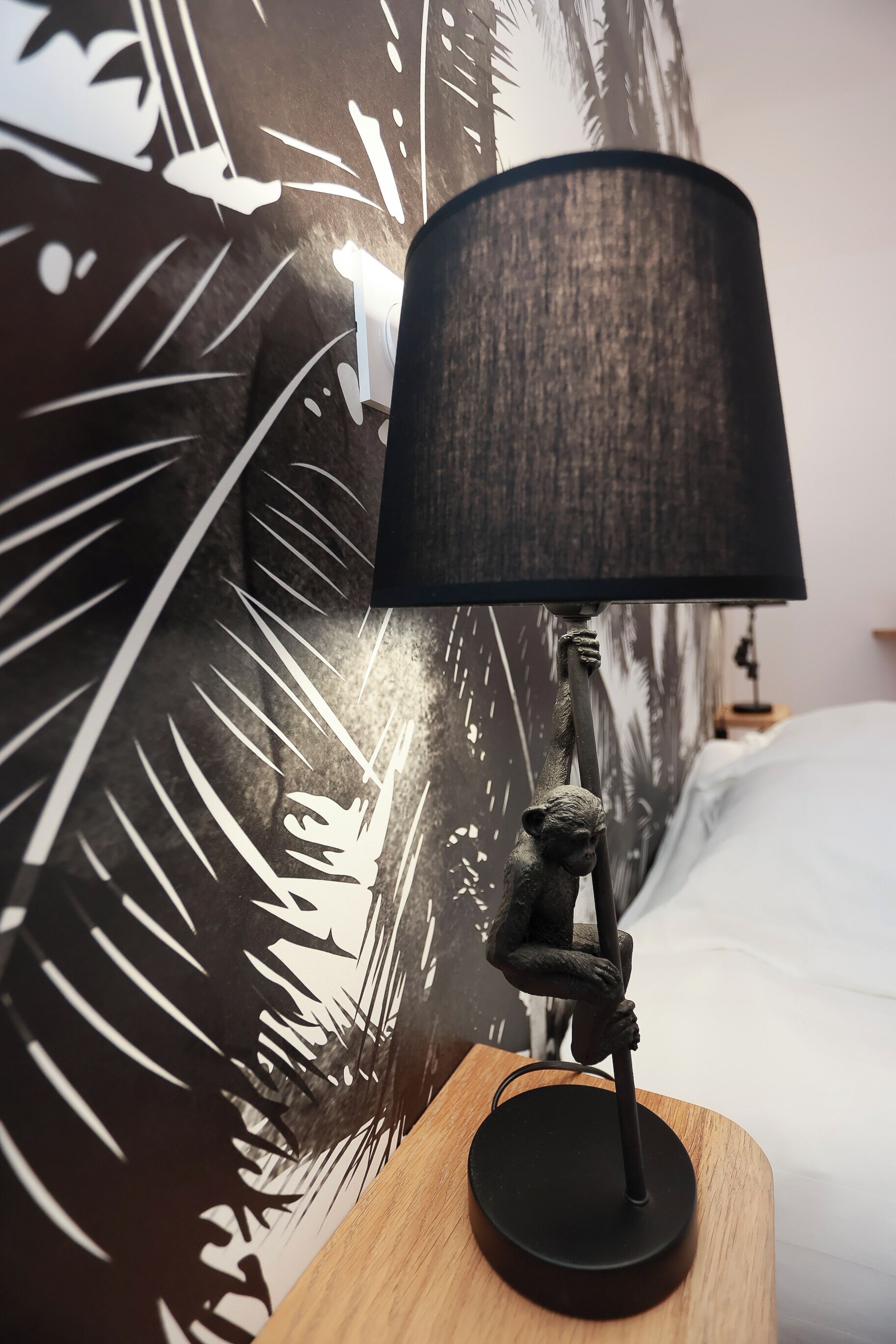A lamp with a black shade on a wooden nightstand.