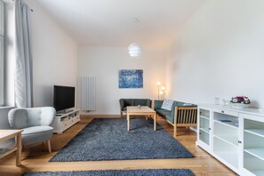 A modern living room with a flat-screen TV, a sofa, a coffee table, a cabinet, and a painting on the wall. - Apartment '2' with Wi-Fi (Heide)