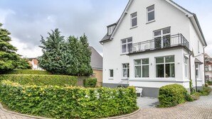 A two-story house with a balcony, a paved driveway, and well-maintained hedges. - Apartment '4' with Wi-Fi (Heide)