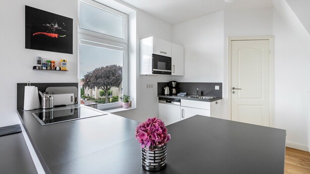 A modern kitchen with a central island, a microwave, and a coffee maker. - Apartment '4' with Wi-Fi (Heide)