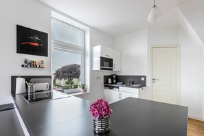 Een moderne keuken met een centraal eiland, een magnetron en een koffiezetapparaat.