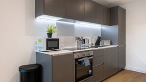A modern kitchen with a microwave, toaster, sink, and oven. - Axis Apartment (Leeds)