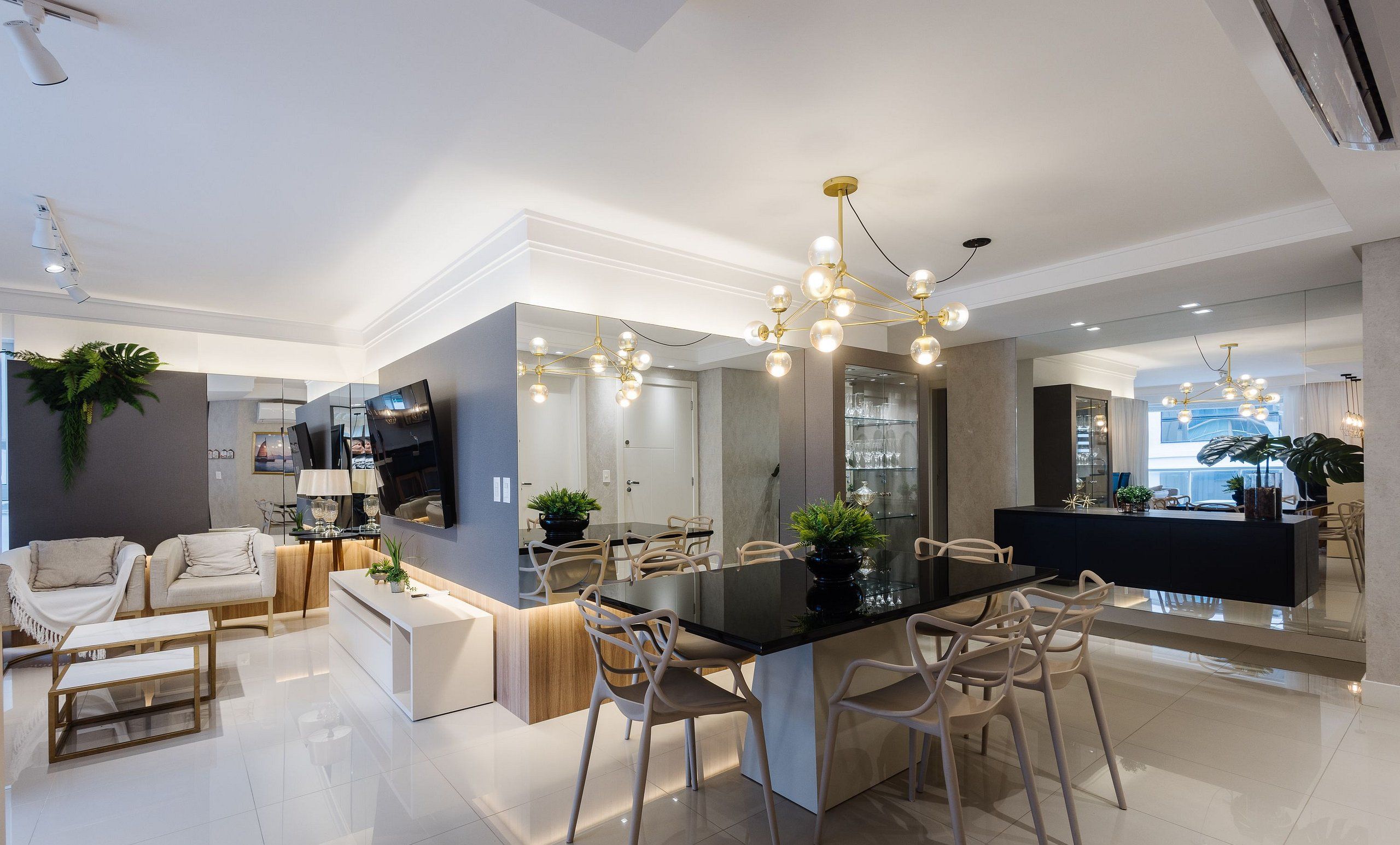 Cozinha moderna com ilha central, iluminação pendente e área de jantar com cadeiras.