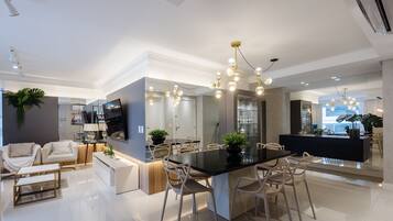 Cozinha moderna com ilha central, iluminação pendente e área de jantar com cadeiras.