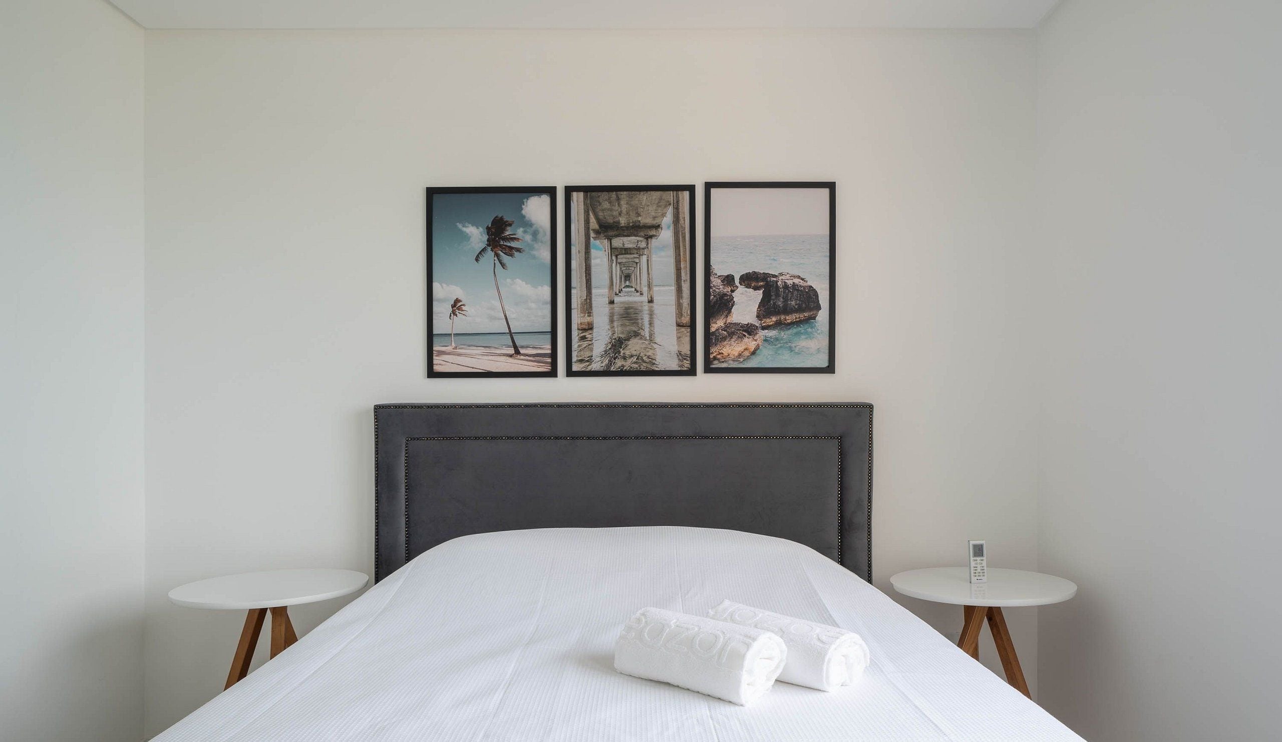 Una habitación de hotel con una cama, dos mesitas de noche y tres cuadros en la pared.