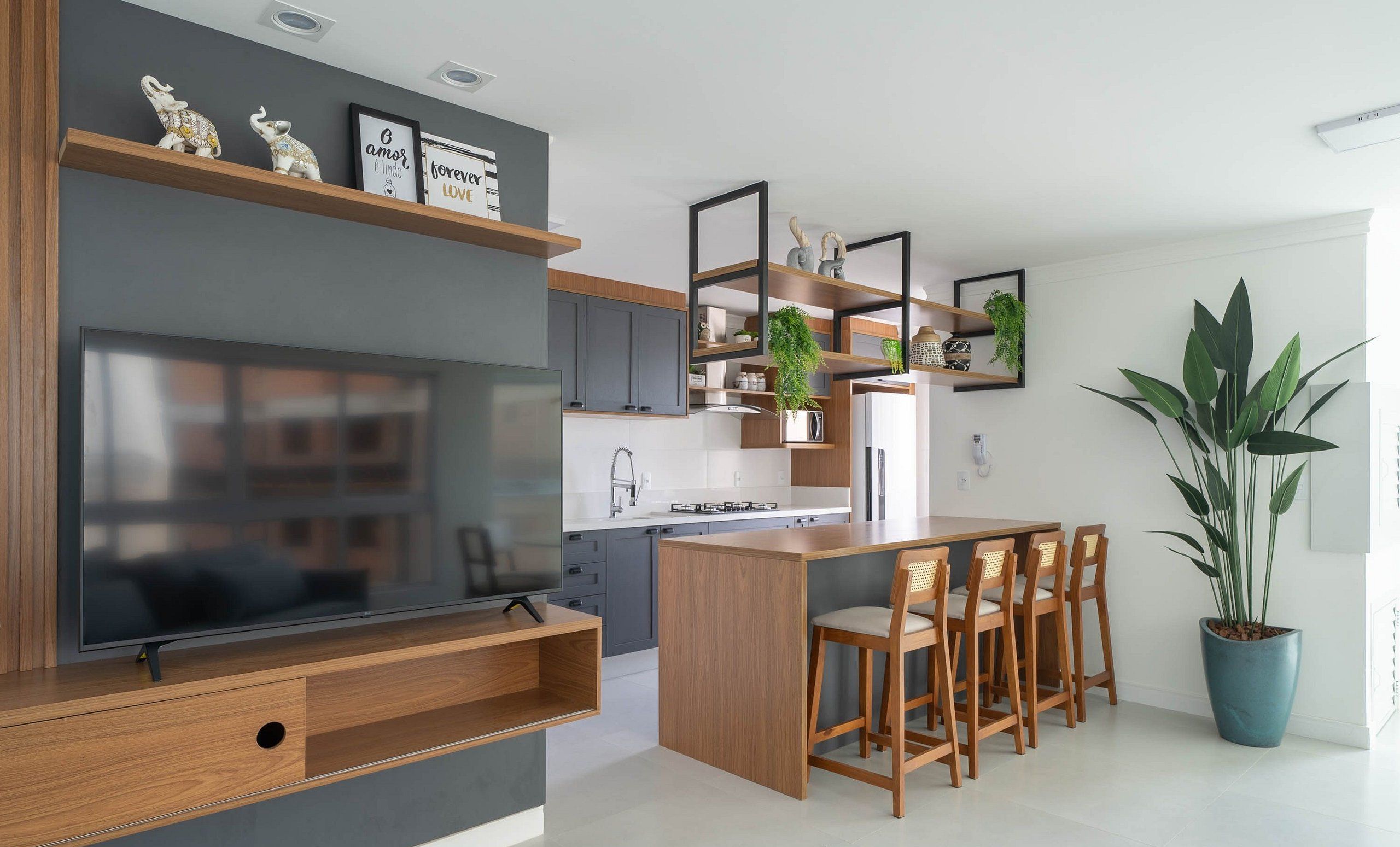 A modern kitchen with a central island, wooden cabinets, and a built-in TV.
