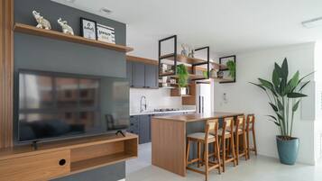 A modern kitchen with a central island, wooden cabinets, and a built-in TV.