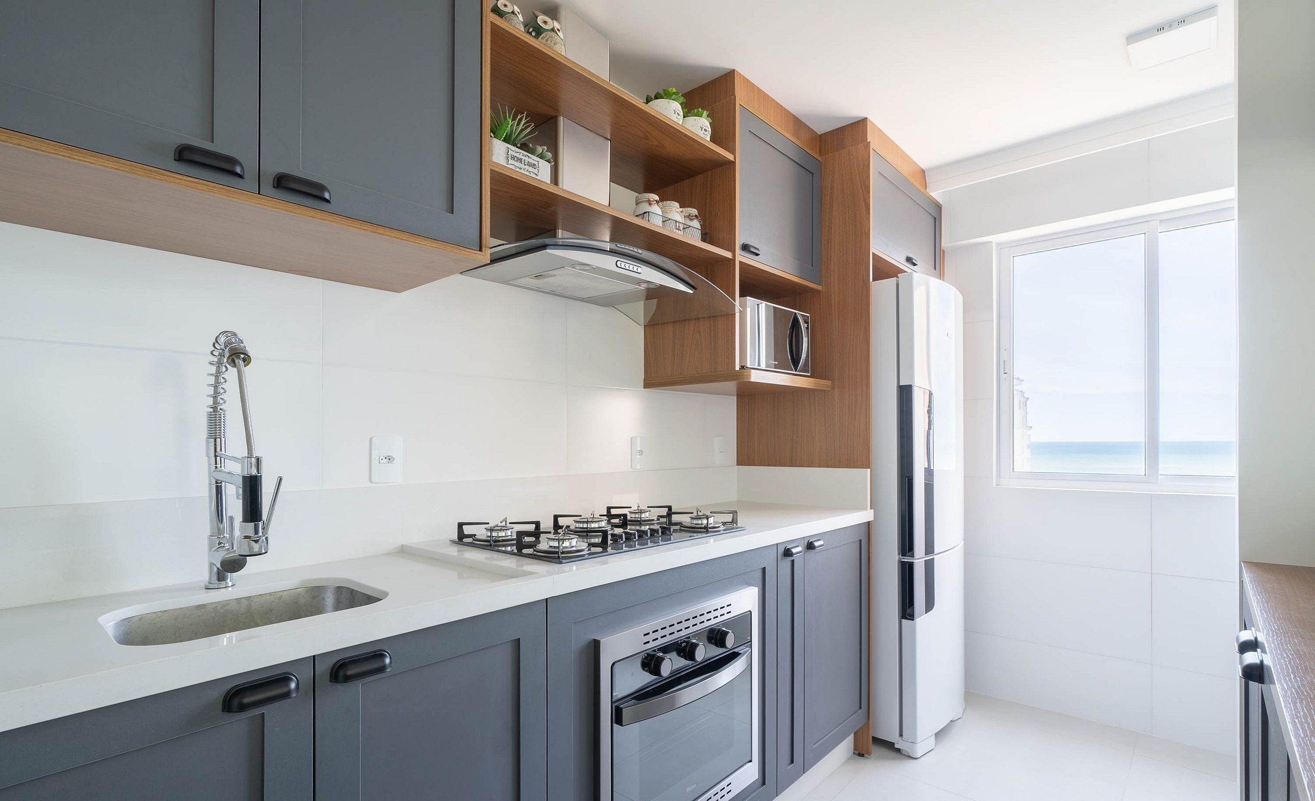 Una cocina moderna con armarios grises, una campana extractora de acero inoxidable, horno empotrado, pileta doble y refrigerador.