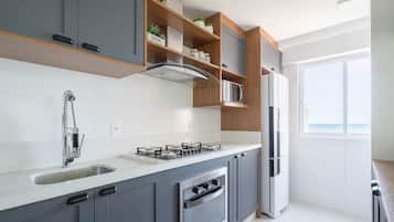 Una cocina moderna con armarios grises, una campana extractora de acero inoxidable, horno empotrado, pileta doble y refrigerador.