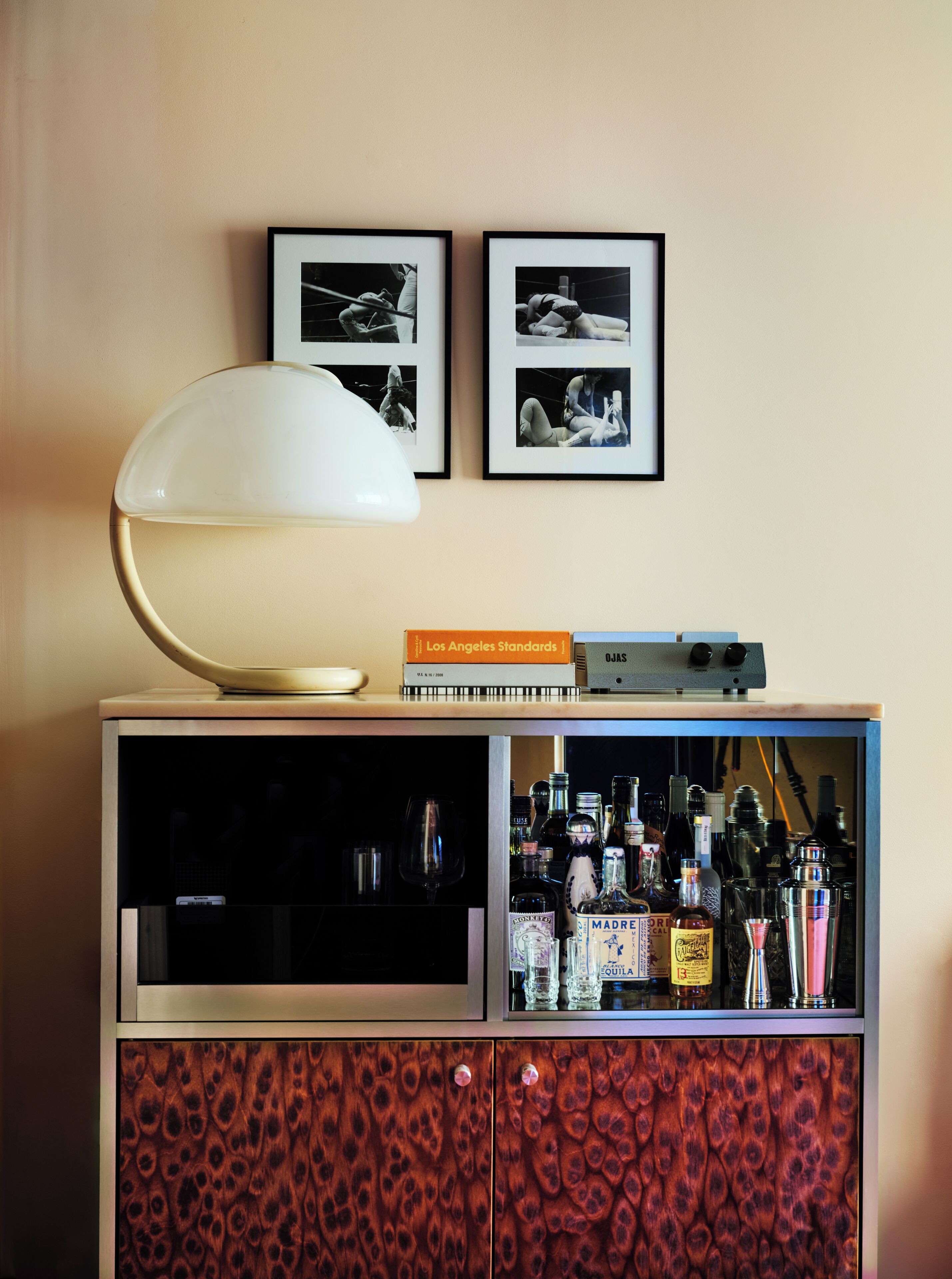 Ein Zimmer mit Lampe, gerahmten Bildern, einem Buch und einer Bar mit Flaschen.