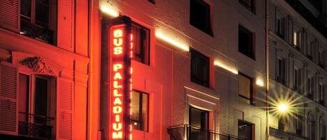 A building with a prominent neon sign reading 'PALLADUM' and a balcony with railings.