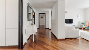 A modern living room with a white sofa, a flat-screen TV mounted on the wall, and a wooden floor. - Brera Apartments in Dateo (Milan)