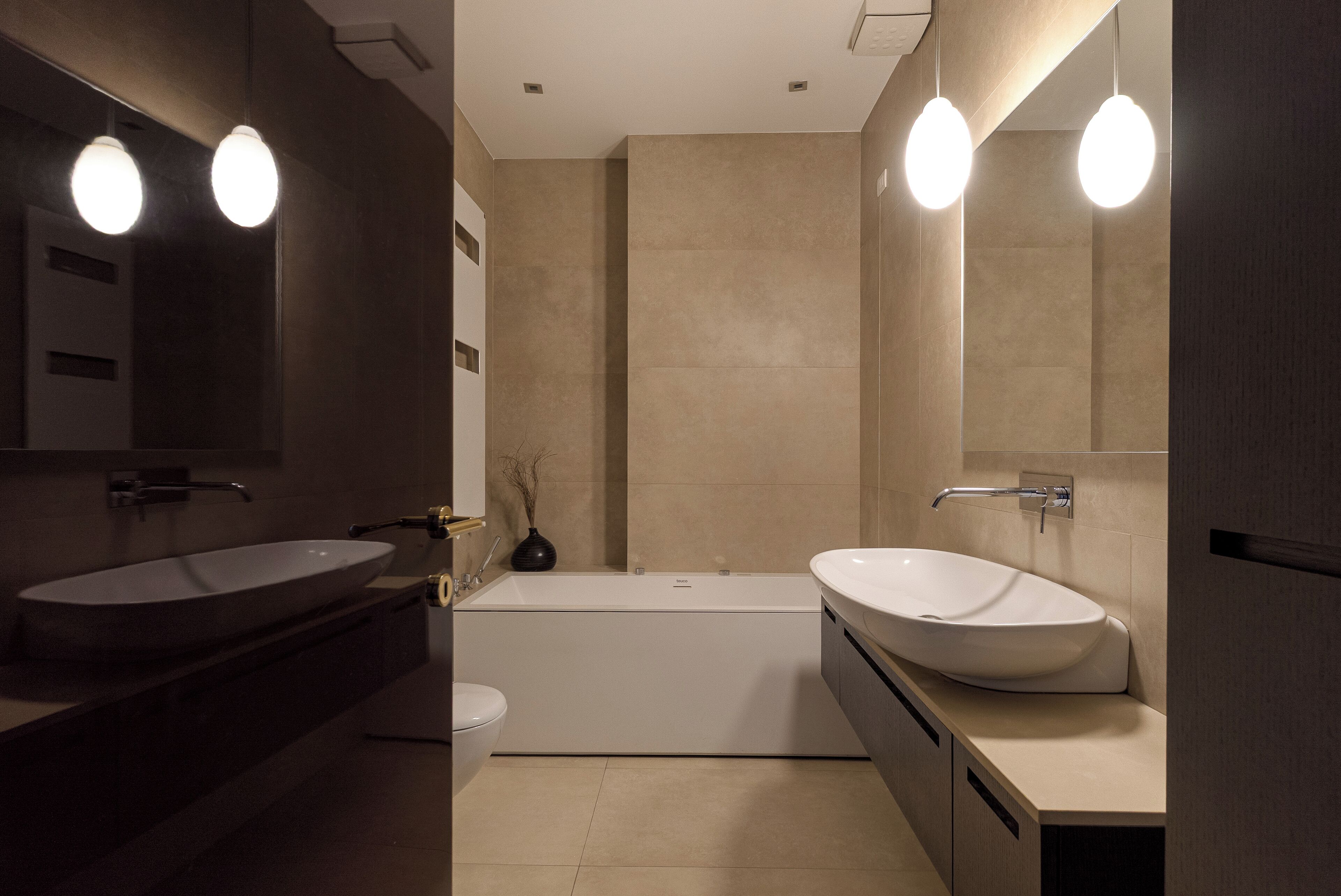 Un baño moderno con dos lavamanos, una bañera y un espejo grande.