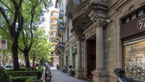 A street with parked scooters, a no parking sign, and a building with ornate architecture. - Brera Apartments in Dateo (Milan)