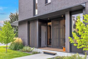 A modern two-story building with a dark brick exterior, large windows, and a wooden deck. - Downtown Luxury Private 2BR at Orren North (Bozeman)