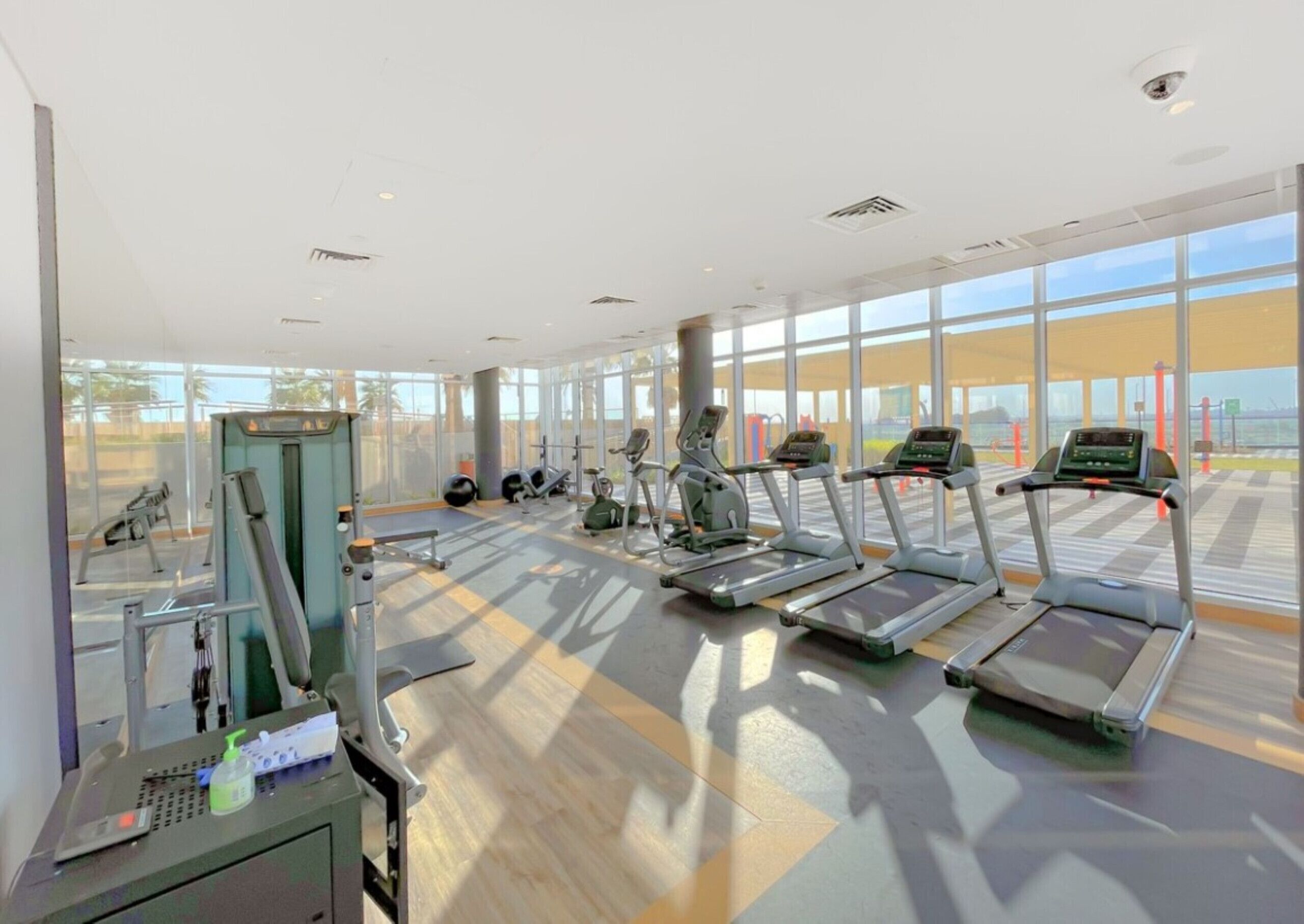 Ein Fitnessstudio mit Laufbändern, Krafttrainingsgeräten und einem Rudergerät.