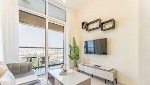 Ein modernes Wohnzimmer mit einer Couch, einem Couchtisch, einem Fernseher und einem Balkon mit Stadtblick.