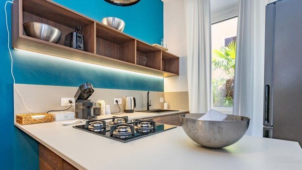 A modern kitchen with a gas stove, a large bowl, and a window with a view of greenery. - Testaccio's Heart - Paulus by Rentbeat  (Roma)