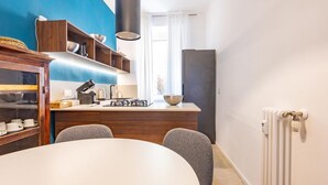 A modern kitchen with a white island, wooden shelves, and a black range hood. - Testaccio's Heart - Paulus by Rentbeat  (Roma)