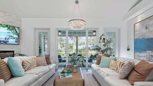 A modern living room with two white sofas, a coffee table, and a chandelier.