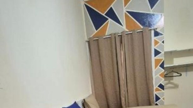 Un lit simple avec un matelas bleu et une couverture grise, un oreiller et une tête de lit beige.