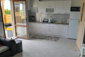 Cozinha compacta com armários brancos, micro-ondas, chaleira e torradeira.