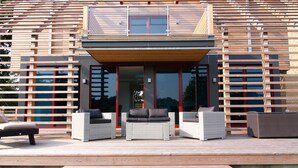 A modern house with a wooden deck, outdoor furniture, and a glass door entrance. - Reihenhaus Reiterchalet in Wendorf (Kuhlen-Wendorf)
