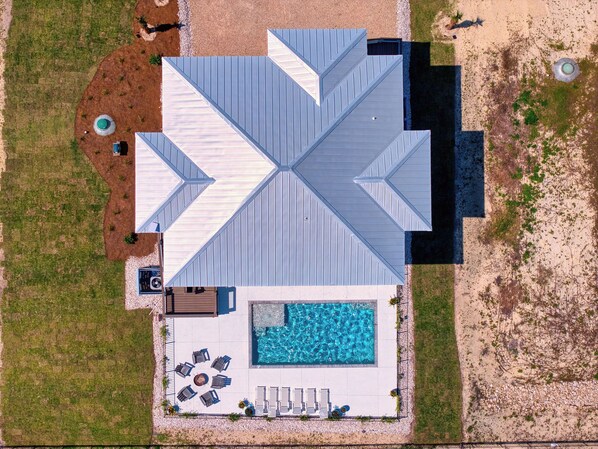 An aerial view of a building with a swimming pool, outdoor seating, and a landscaped area.
