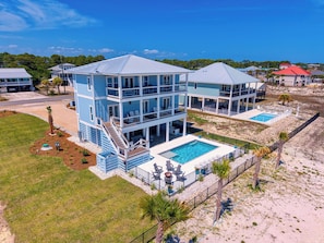 A multi-story beachfront property with a swimming pool, multiple balconies, and a covered patio area.