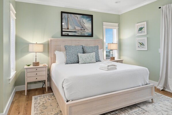 A bedroom with a bed, nightstands, a window, and a painting on the wall.