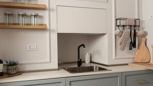 Een keuken met een spoelbak van roestvrij staal, houten planken en een keukengerei rek.
