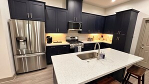 A modern kitchen with dark cabinets, stainless steel appliances, and a granite countertop.
