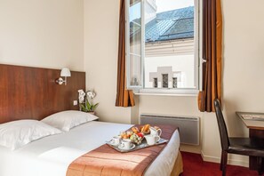 Ein Hotelzimmer mit Bett, Frühstückswagen, Fenster und Stuhl.