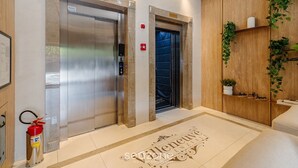 Two elevators with marble surrounds, a fire extinguisher, and a welcome mat with 'Valiente' text. - 2BR apt w/ BBQ 750m From Beach Rvn2003 (Itapema)