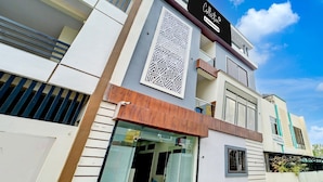 A modern building with a prominent sign, a geometric decorative panel, and a glass entrance. - Collection O Hotel Sp14 (Indore)