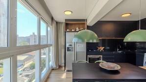 Une cuisine moderne avec vue sur la ville, de grandes fenêtres et des luminaires suspendus.