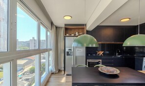 A modern kitchen with large windows, a dining area, and a view of the cityscape.