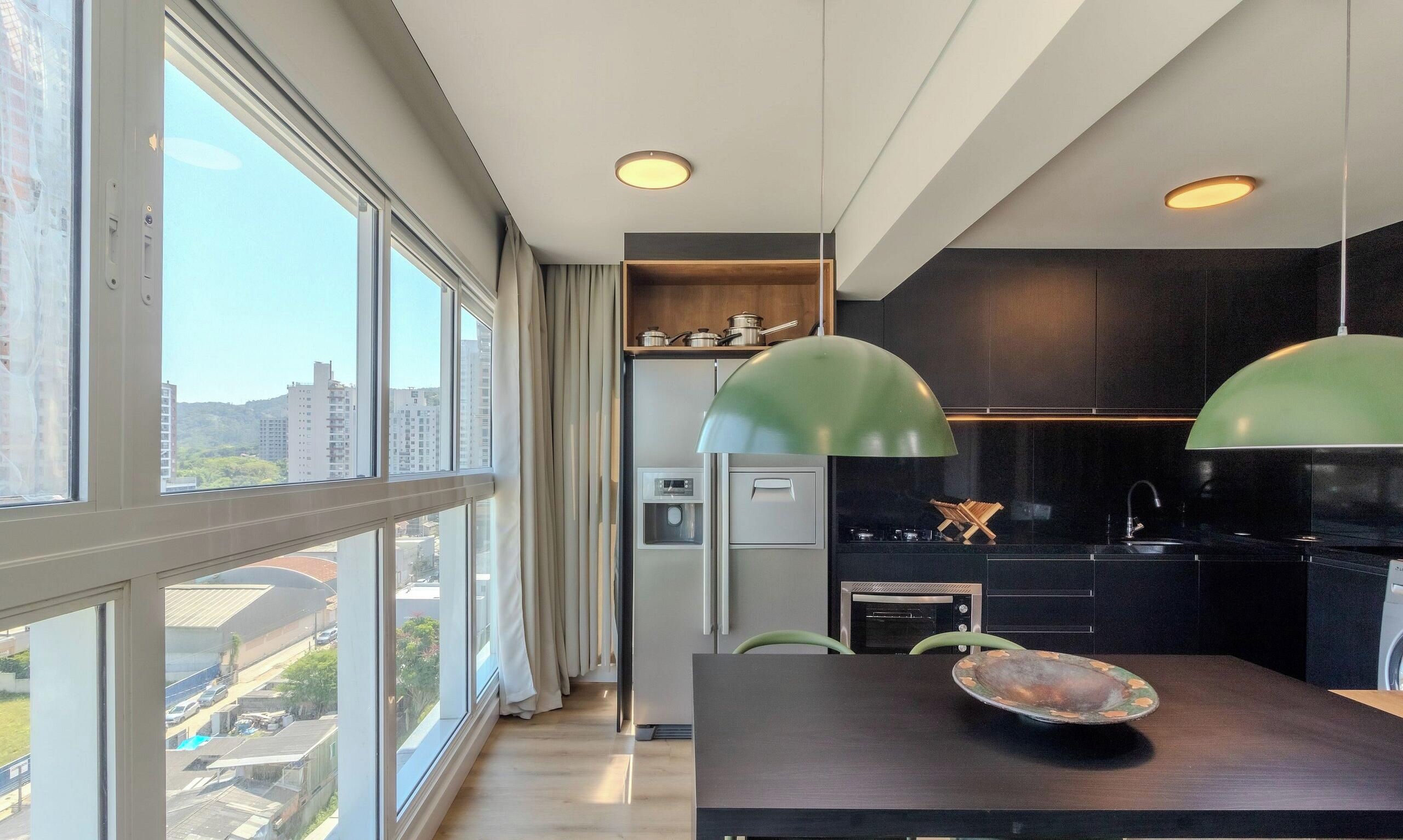 A modern kitchen with a large window, a dining area with a table and chairs, and a view of the cityscape.