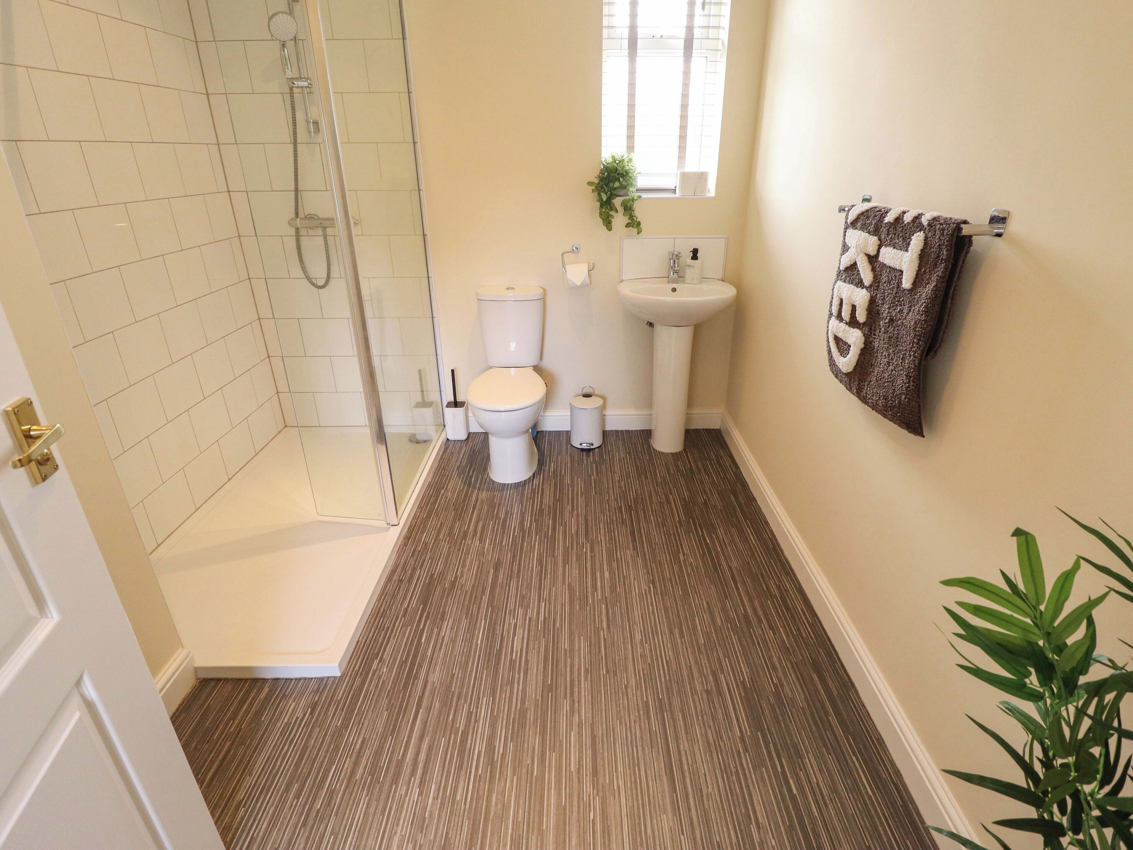 A bathroom with a glass shower enclosure, a toilet, a sink, and a towel rack.