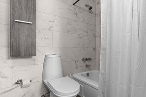 Un baño con inodoro, bañera y ducha.