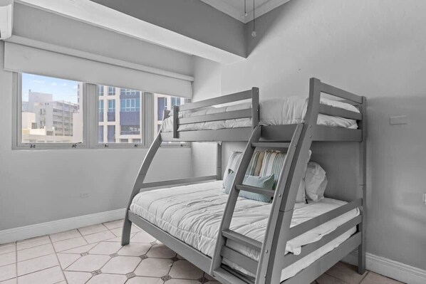 A bunk bed in a room with large windows and a tiled floor.