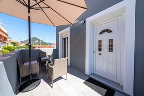 A patio with wicker furniture, a door, and a view of a mountain. - Country House 'Kate' with Mountain View, Wi-Fi and Air Conditioning (Κερκυρα)