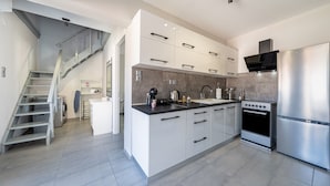 A modern kitchen with a central island, stainless steel appliances, and a staircase leading to another room. - Country House 'Kate' with Mountain View, Wi-Fi and Air Conditioning (Κερκυρα)