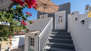 A staircase leading to a white door, a small balcony with a white railing, and a red flower bush. - Country House 'Kate' with Mountain View, Wi-Fi and Air Conditioning (Κερκυρα)