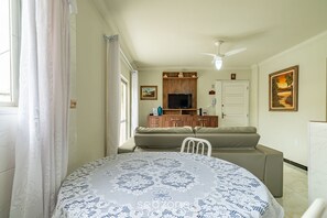 A living room with a sofa, a television, and a dining table with a patterned tablecloth. - 2BR Apt 260m From Canto Beach Itapema Rtl0302 (Itapema)