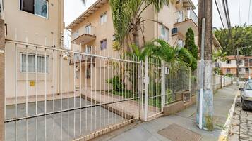 A residential building with a gated entrance, a balcony, and a palm tree.